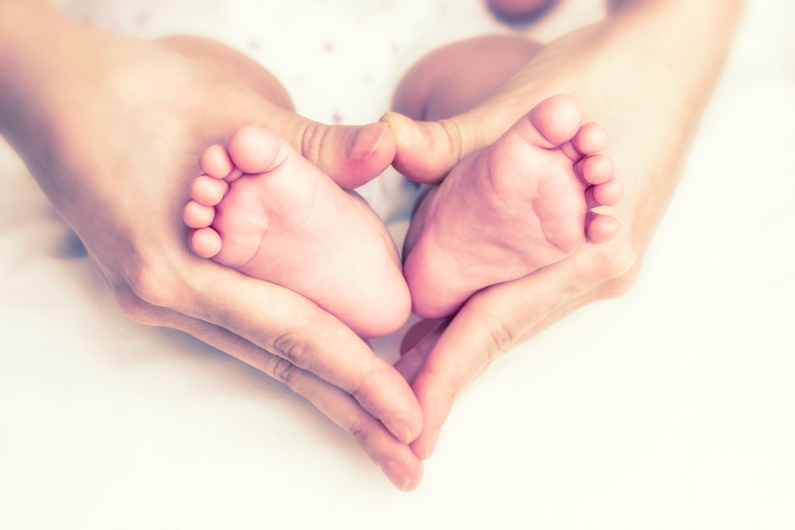 baby's feet in heart shaped hands