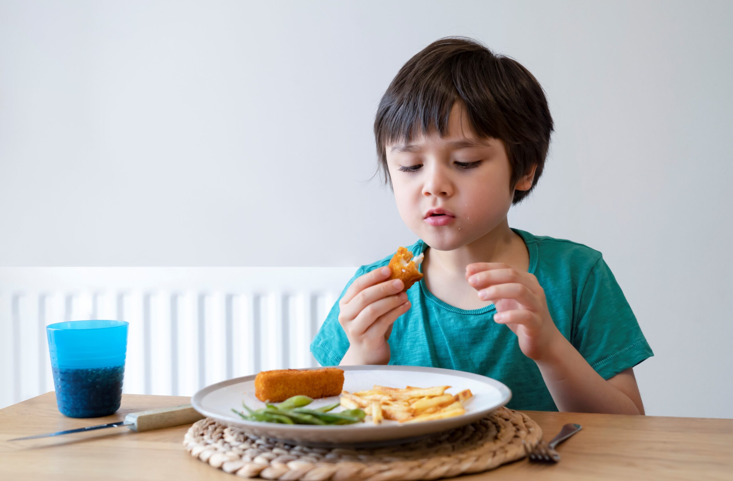 child eating fishstick at table